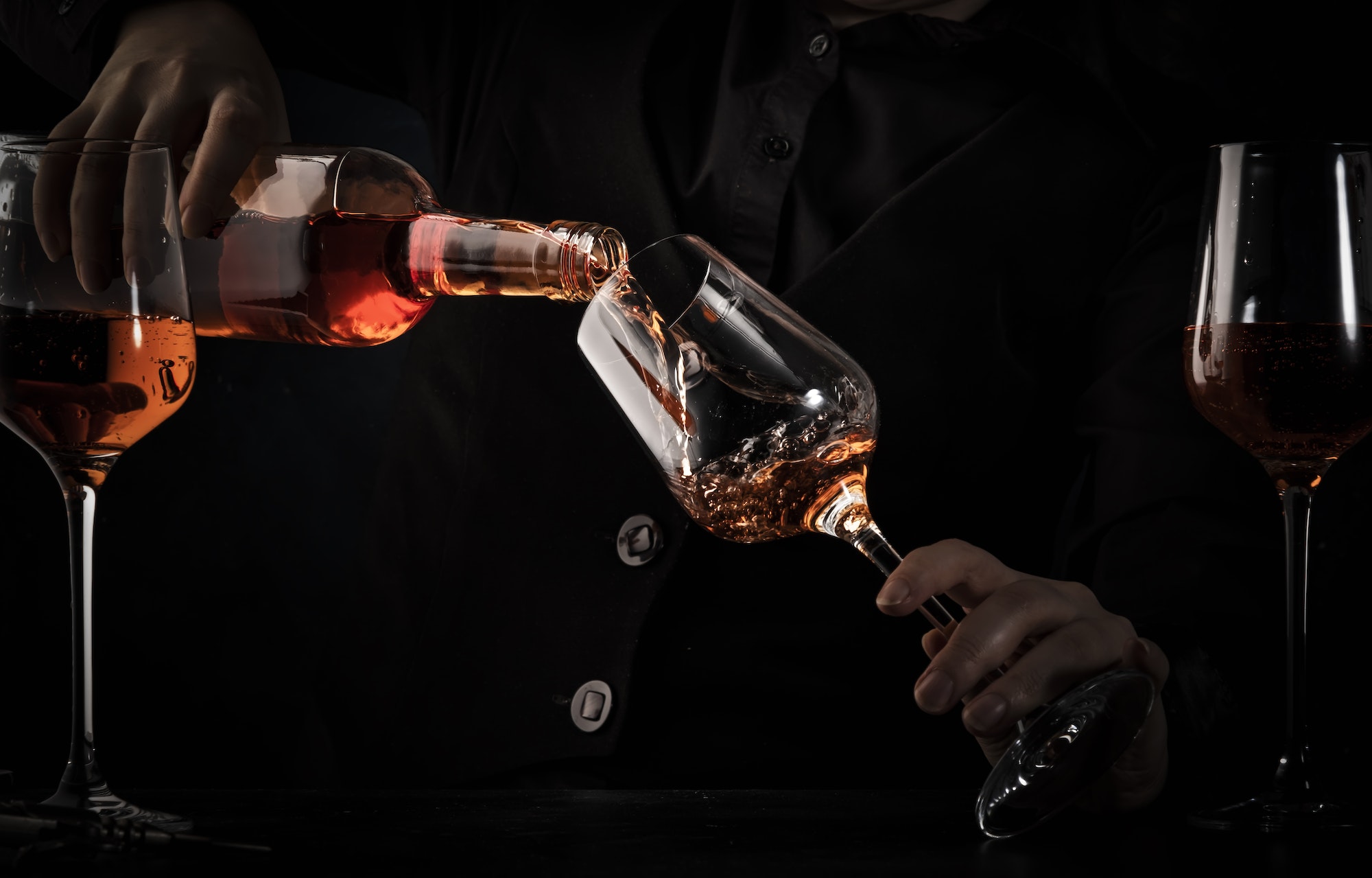 Sommelier pouring rose wine into glass